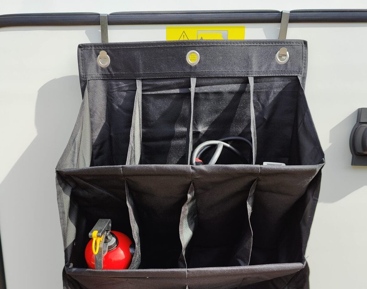 Torba na drzwiach garażu w kamperze z gaśnicą i zestawem awaryjnym